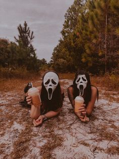 two women with masks on their faces are holding drinks in the middle of a field