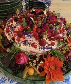 there is a cake with berries and flowers on the top, surrounded by other desserts