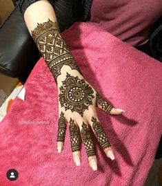 henna tattoo on the hand of a woman sitting in a chair with pink blanket