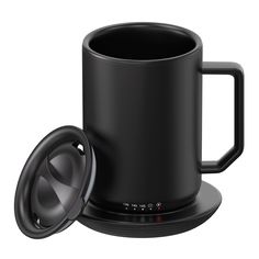 a black coffee mug with a speaker on the side and an empty cup next to it