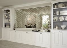 a kitchen with white cabinets and glass tile backsplash in the back wall area