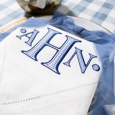 an embroidered monogrammed napkin with the word ahn on it sitting on a plate