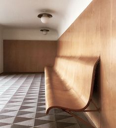 a wooden bench sitting in the middle of a room with checkered floor and walls