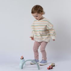 Meet our delightful horizontal stripe sweatshirt from Aneby, adorned with soft pastel hues of green, blue, and peach. This comfortable, boxy fit design sports dropped shoulder set-in sleeves and a neat V-stitch at the front neck. Ideal for any young style seeker, this sweatshirt shines with its gender-neutral tones, suitable for both boys and girls. Inspired by the traditional football jersey, the 'V' stitch detailing adds a sporty charm. Pair it with ribbed leggings or bicycle shorts for an eff Stripe Sweatshirt, Stripe Jumper, Jumper Designs, Hues Of Green, Bicycle Shorts, Garment Pattern, V Stitch, Striped Sweatshirts, Ribbed Leggings