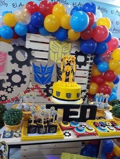 a table topped with cake and cupcakes covered in balloons