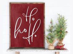 a wooden sign that says ho ho ho on it next to some christmas tree branches