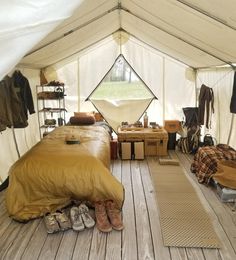 a bed sitting inside of a tent next to a pile of luggage on top of a wooden floor