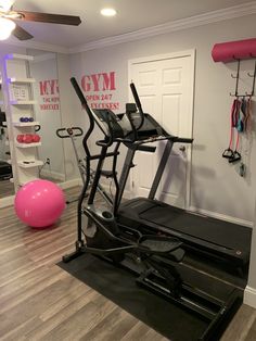 an exercise room with treadmills, pink ball and gym equipment on the floor