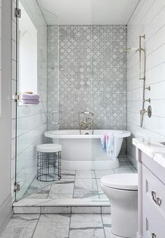 a bathroom with a white bathtub, toilet and sink next to a walk in shower