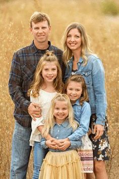 a family posing for a photo in the middle of a field with tall brown grass