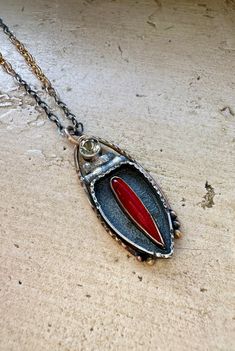 "Perfect for warming the winter months, this pendant features a luminous, scarlet marquis of Rosarita \"stone\" (actually a glass byproduct of gold smelting) on a bed of textured and oxidized sterling silver (recycled). Above, sits a pale green amethyst gemstone. the whole construction is surrounded by thick,textured 14k gold fill wire . The bezel for the Rosarita, and short lengths in the cable chain are also 14k gold fill. The effect is regal.  *recycled sterling silver *14k gold fill *Rosarita stone *green amethyst *commercial cable chain of adjustable length (the hook slides into any link) *hand made hook closure *coral accent *simple engraving on backplate *oxidized and lightly polished for contrast chain length: up to 19 inches  pendant height:1 3/4 inch width: 5/8 inch Ships insured Unique Marquise Gemstone Jewelry, Gemstone Necklace Marquise Cut For Gift, Gift Gemstone Necklace With Marquise Cut, Gift Marquise Cut Gemstone Necklace, Unique Marquise Jewelry As A Gift, Unique Marquise Jewelry For Gifts, Marquise Cut Gemstone Necklace For Gift, Mixed Stone Necklace, Coral Accents