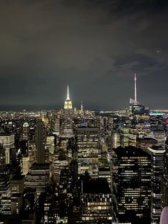 the city skyline is lit up at night, with skyscrapers in the foreground