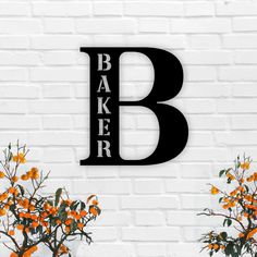 a sign that says baker on the side of a brick wall next to some flowers