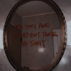 a mirror with graffiti written on it in a bathroom next to a toilet paper dispenser