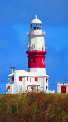 a red and white lighthouse on top of a hill