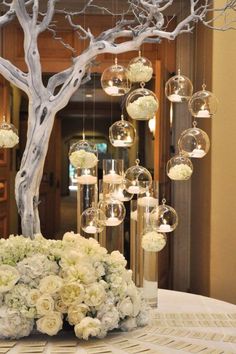 a centerpiece with flowers and hanging glass globes is displayed on a round table