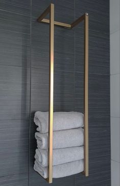 a towel rack in the corner of a bathroom with towels hanging on it's sides