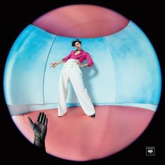 a woman in pink shirt and white pants standing next to a giant object