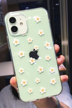 a person holding up an iphone case with daisies on it