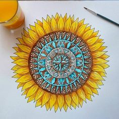 a drawing of a sunflower with blue and yellow colors on it, next to a glass of orange juice