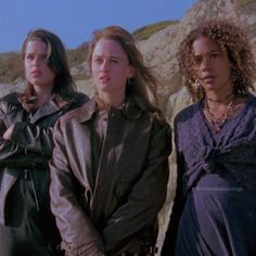 three women standing next to each other on the beach