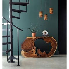 a wooden table sitting next to a spiral stair case in a room with green walls