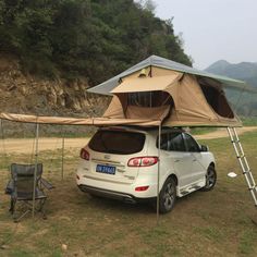 a white car parked in front of a tent on the side of a hill with a ladder attached to it