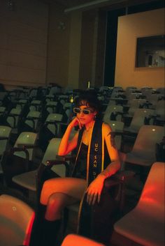 a woman sitting on top of a chair in front of an empty auditorium filled with chairs