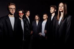 a group of men standing next to each other in front of a black background with red glasses