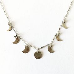 "Silver moon phase necklace.  This delicate necklace is made from 7 small hammered silver pendants to represent the phases of the moon.   The central full moon pendant measures approximately 0.8cm.  The necklace is on a short sterling silver cable chain that measures 15\" long so that it is a short choker style.  2\" of Additional links have been added to the end of the chain so there is  room for adjustment in the length. If you would like this necklace made on a longer chain please request a c Adjustable Silver Necklace With Moon Phase, Sterling Silver Moon Phase Charm Necklace, Sterling Silver Charm Necklace With Moon Phase Pendant, Silver Charm Necklace With Moon Phase Round Pendant, Silver Dangle Charm Necklace With Moon Charm, Adjustable Sterling Silver Moon Phase Necklace, Silver Crescent Moon Phase Charm Necklace, Sterling Silver Half Moon Charm Necklace, Adjustable Crescent Moon Phase Charm Necklace