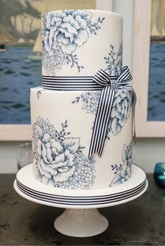 a three tiered cake with blue and white flowers on it is sitting on a table