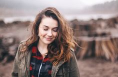 a woman standing in the dirt with her eyes closed and hair blowing in the wind