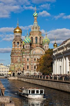 a boat traveling down a river next to a tall building with domes on it's sides