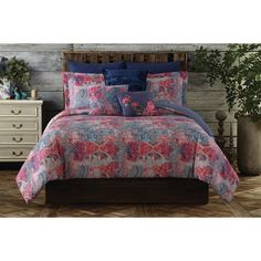 a bed with pink and blue comforters on top of it next to a dresser