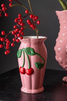 a pink vase with berries painted on it