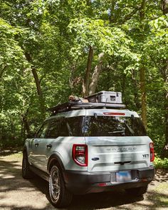 an suv parked in the woods with its roof rack mounted to it's trunk