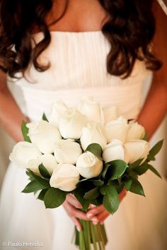 a bride holding a bouquet of white roses