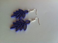 two pairs of earrings with leaves on them sitting on top of a white countertop