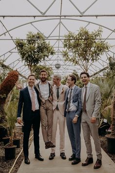 Groomsmen pose for photo in tonal neutral suits surrounded by plants Groomsmen Casual Wedding, Mixed Groomsmen Attire, Different Color Suits Groomsmen, Multicolor Groomsmen Attire, Mismatched Suits Wedding, Mix Matched Groomsmen, Formal Garden Party Attire Men, Groomsmen Ties Mismatched