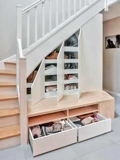 an under the stairs storage area with drawers underneath it and shoes on the bottom shelf