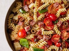 a pasta salad with tomatoes, olives, peppers and ham