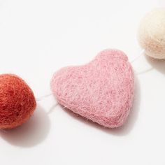 two balls of wool are next to a heart - shaped ball on a string,