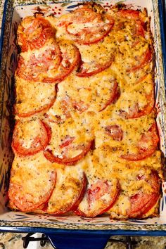 a casserole dish with tomatoes and cheese in it sitting on a counter top