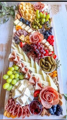 an assortment of cheeses, fruits and meats on a platter