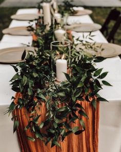 a long table with candles and greenery is set up for an outdoor dinner party