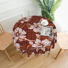 the table is covered with a brown and white floral print cloth, next to two wooden chairs