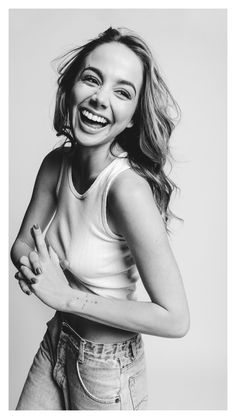 a black and white photo of a smiling woman with her arms crossed, looking at the camera