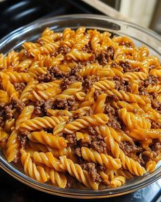 a glass bowl filled with pasta and ground beef