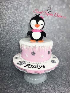 a pink and white cake with a penguin on top