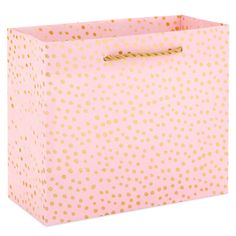 a pink and gold polka dot gift bag with rope on the handle, isolated against a white background